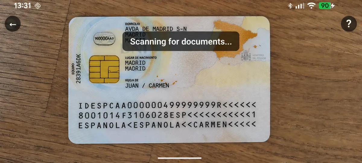 Phone held sideways with the camera open, an ID card filling the frame and the MRZ at the bottom clearly readable. Caption overlay: "Scanning for documents…"